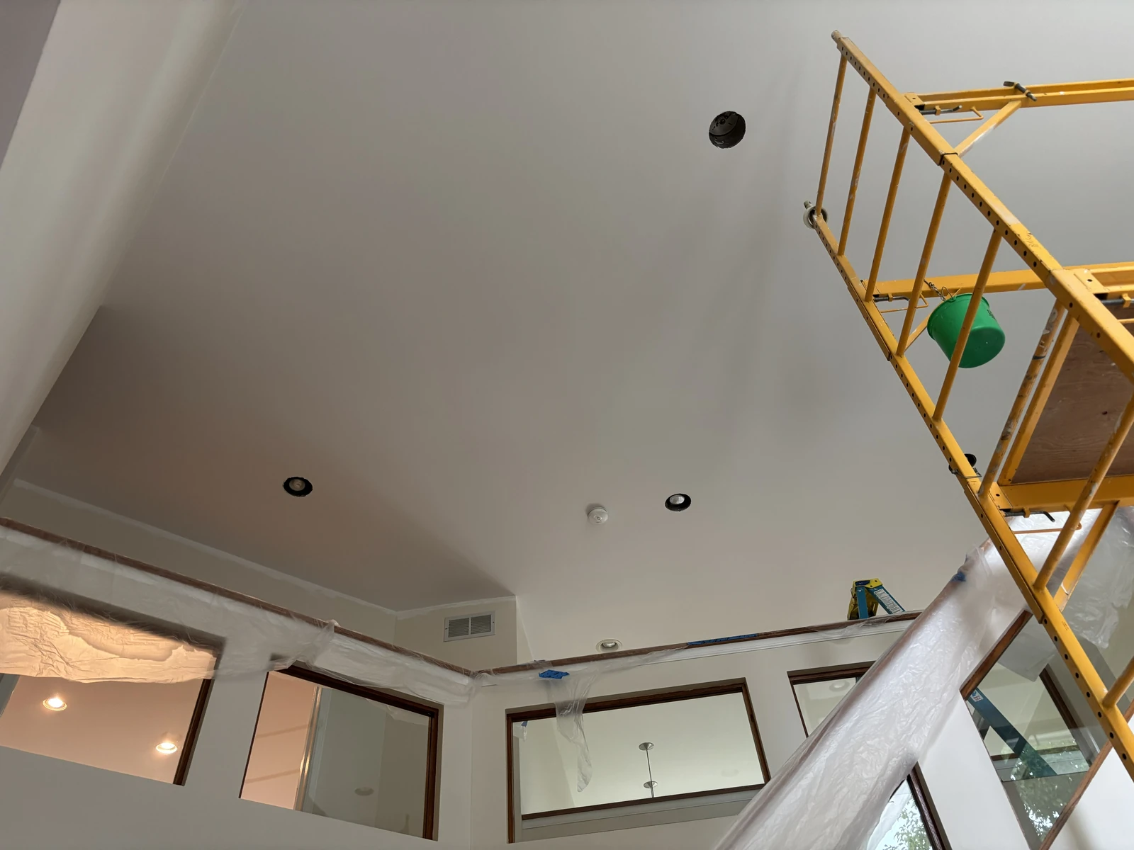 Interior ceiling painting project with scaffolding and protected surrounding surfaces