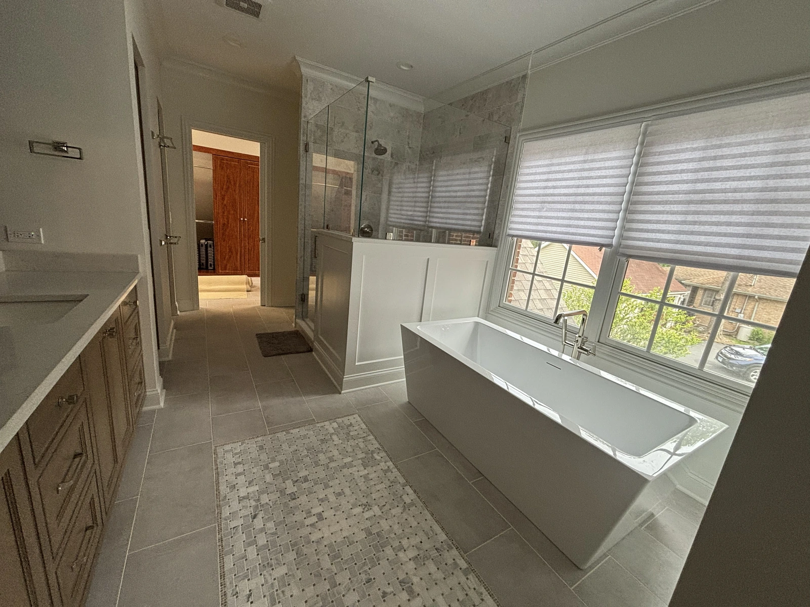Completed master bathroom with a freestanding tub, glass shower, tile floor, and wood vanity