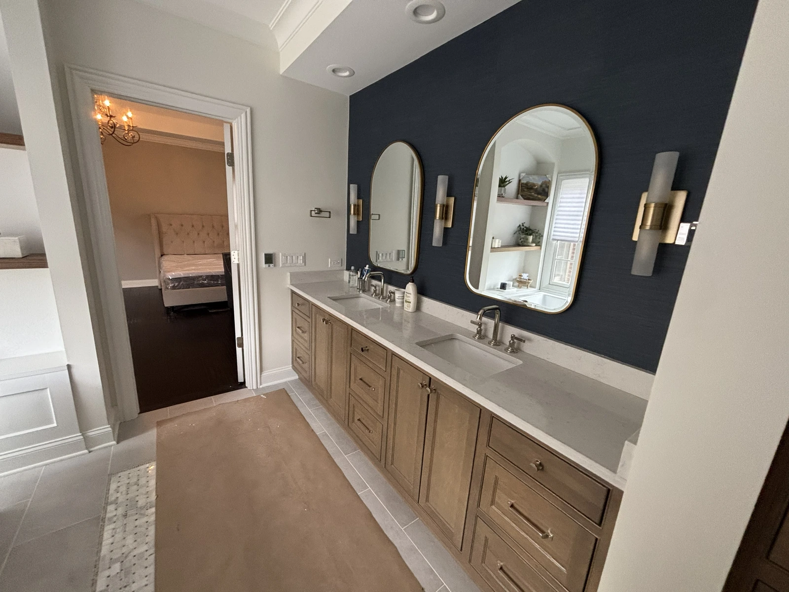Double vanity with twin sinks, arched mirrors, wall lights, and a deep blue accent wall